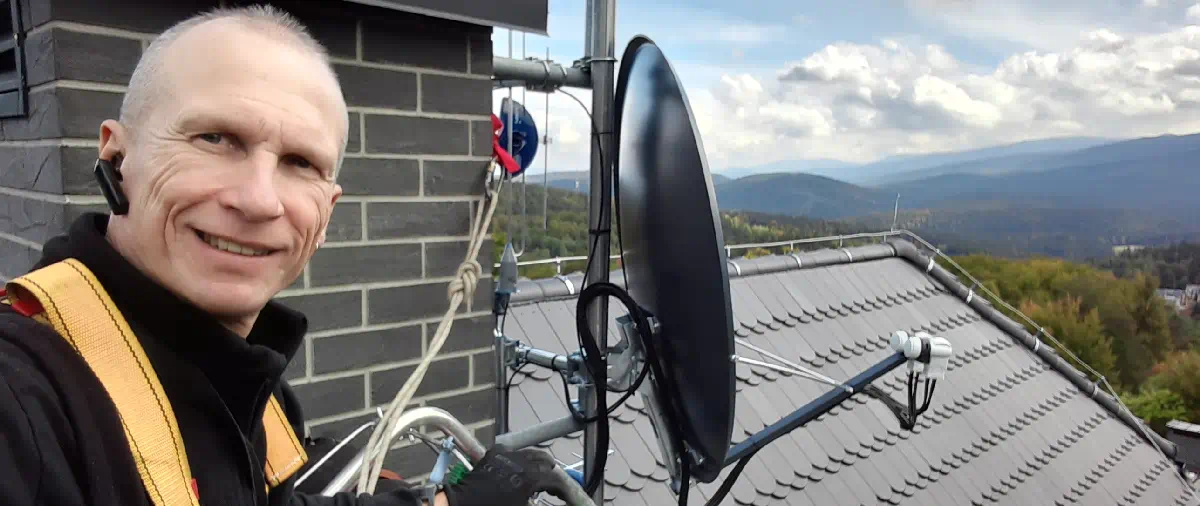 Instalator na dachu przy antenie telewizyjnej