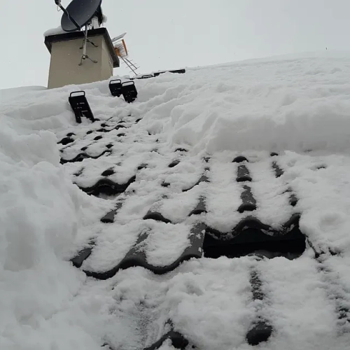 Stworzona przez serwisanta droga do anten na stromym dachu pokrytym śniegiem i lodem